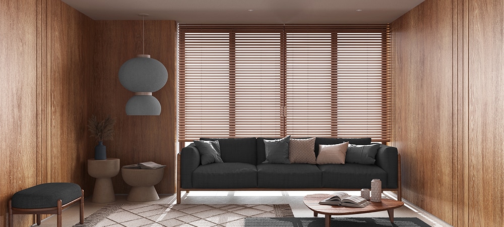 Fabric sofa with pillows, big window with venetian blinds, carpets and decors