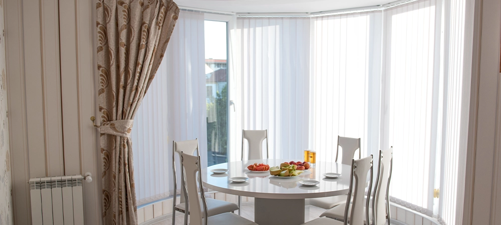 A table with fruits and chairs in light coloured bow window, bow windows custom blinds