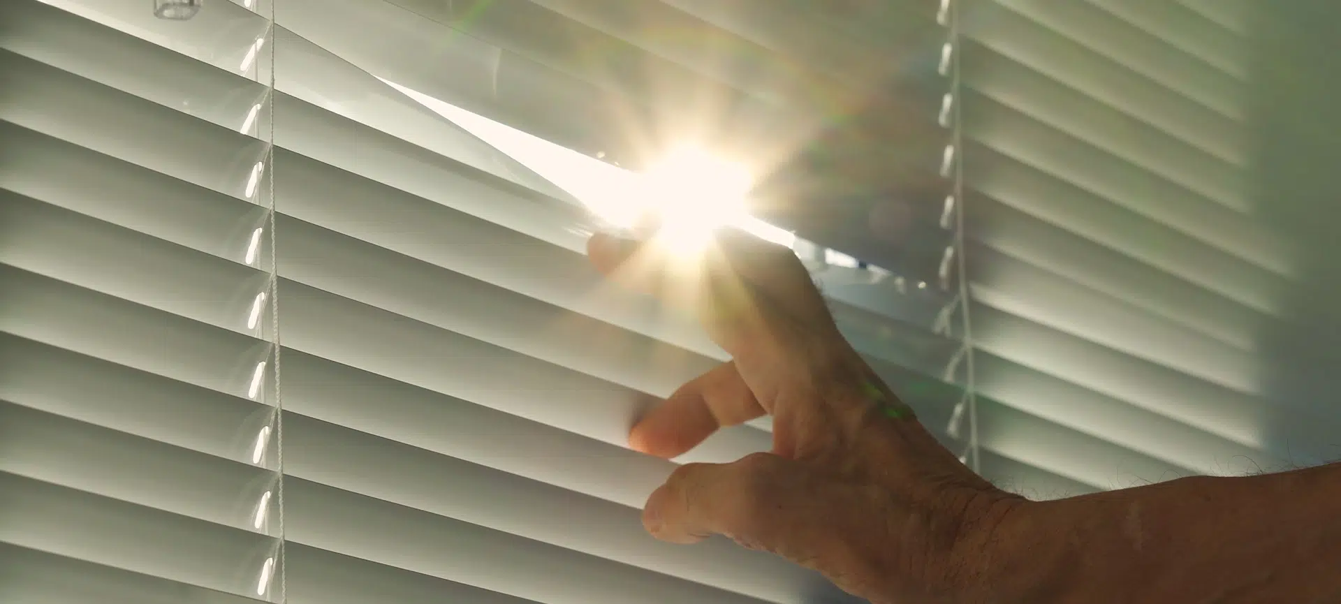 When a man's hand opens the window blinds, a bright blinding ray of sunlight streams in, filling the space with warmth and light, as if welcoming all the inhabitants of the house.