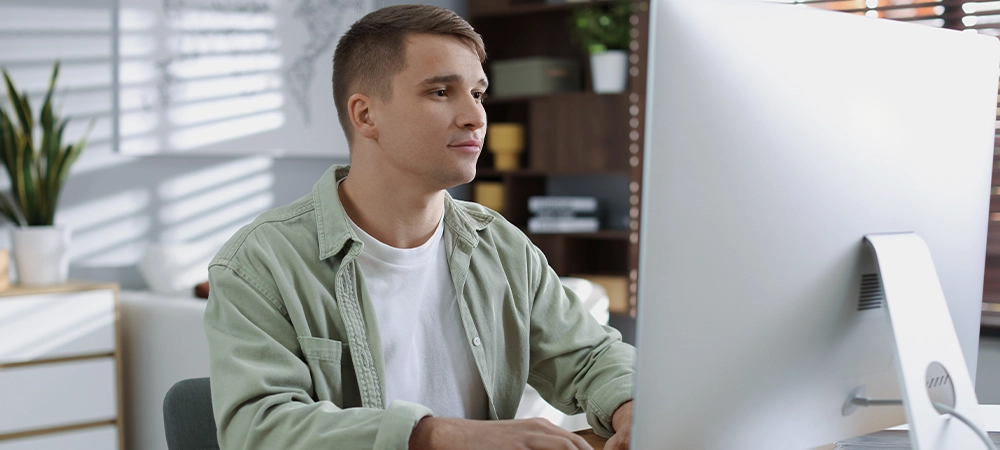 Handsome man working with computer at desk indoors. Home office