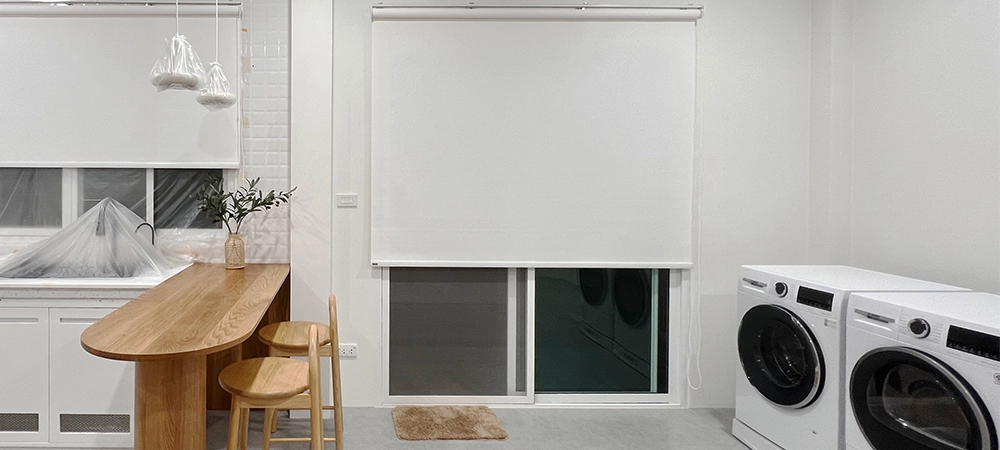 well-organized kitchen and laundry room with a washer and dryer. There are shelves for storing supplies. The window and the door protect the light from outside by roller blinds.