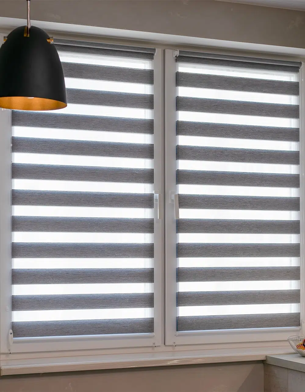 Zebra blinds installed on kitchen windows, featuring alternating sheer and opaque fabric stripes. Double roller shades provide adjustable light control while adding a modern touch to interior space.