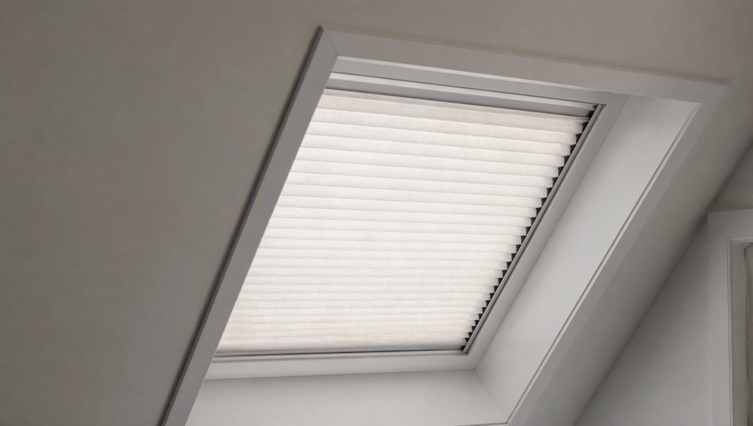 Motorized cellular skylight shade held flat in side channels inside an angled roof window